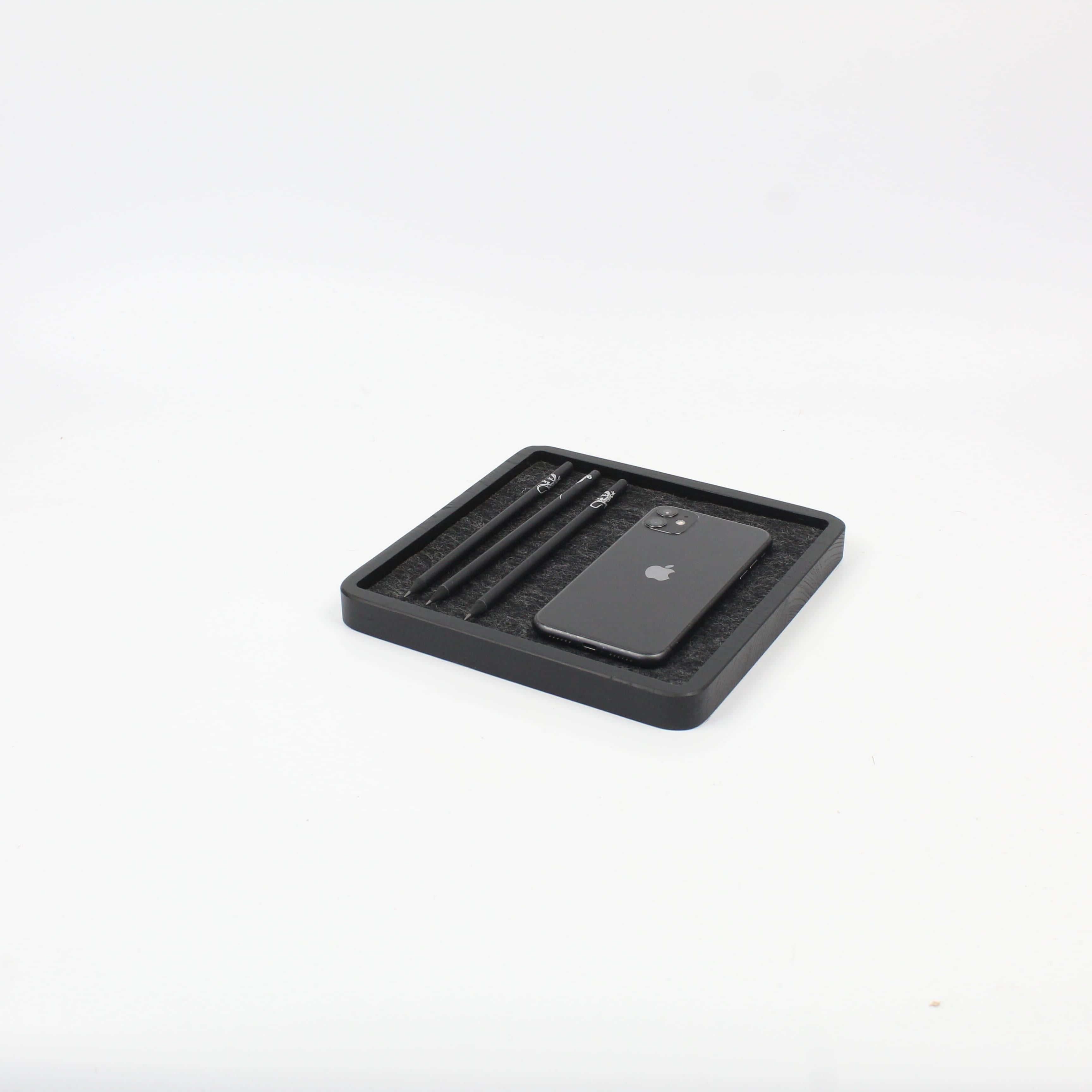 Black oak square catch all desk tray holding a phone and pens, ideal for organizing desk accessories.