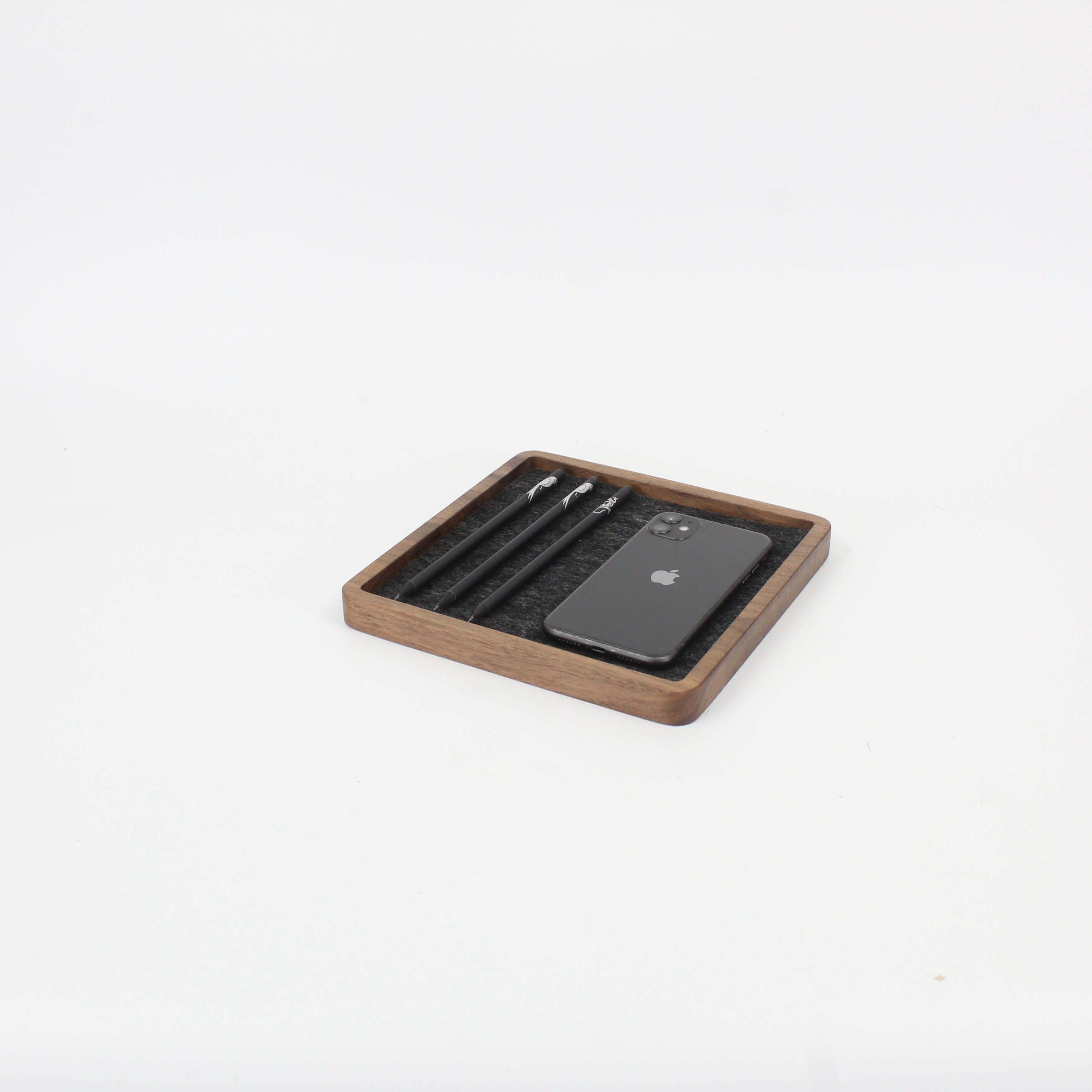 Walnut square catch all tray organizing a phone and pens, ideal desk accessories for a tidy workspace.