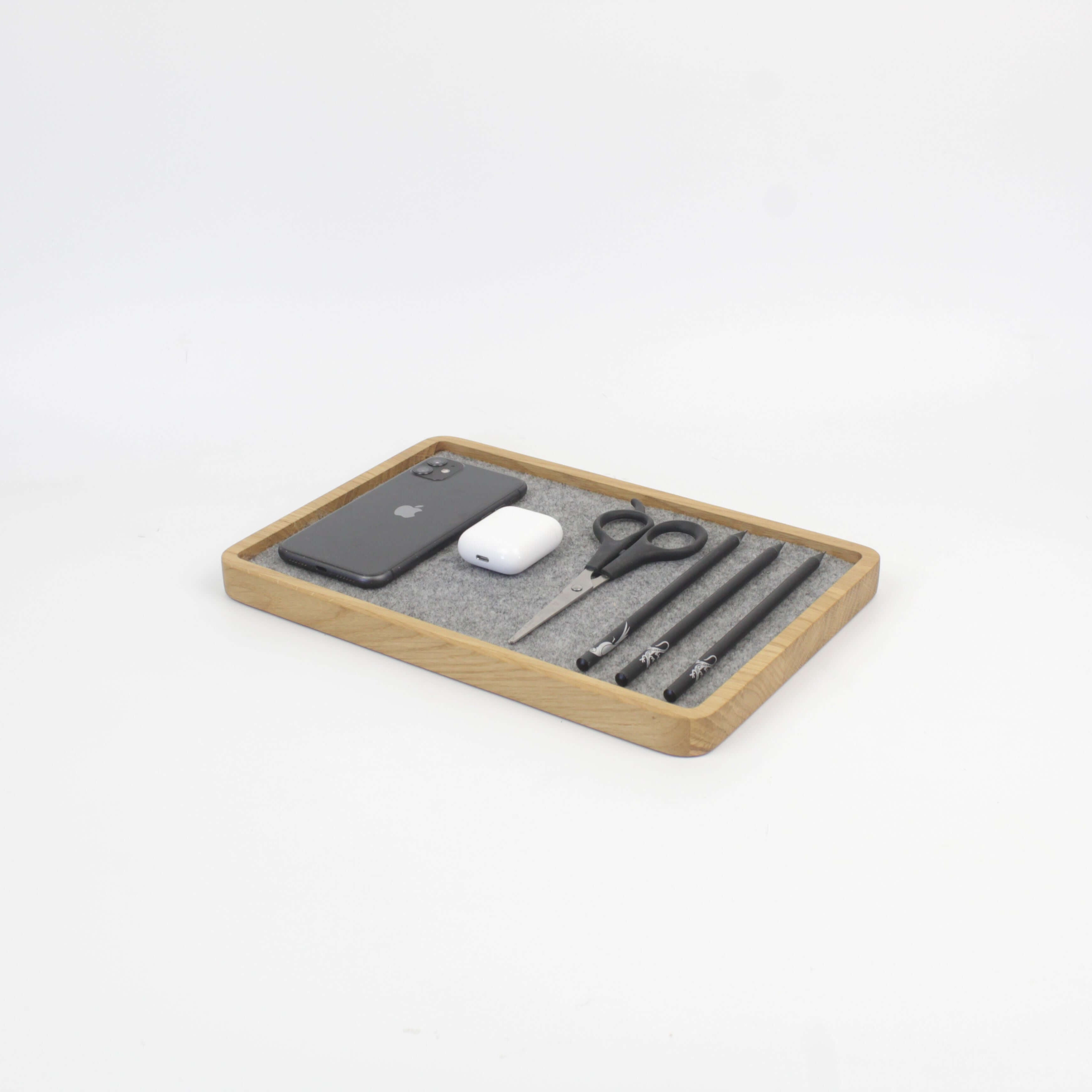 Catch all tray in oak with phone, AirPods, scissors, and pens for desk organization.