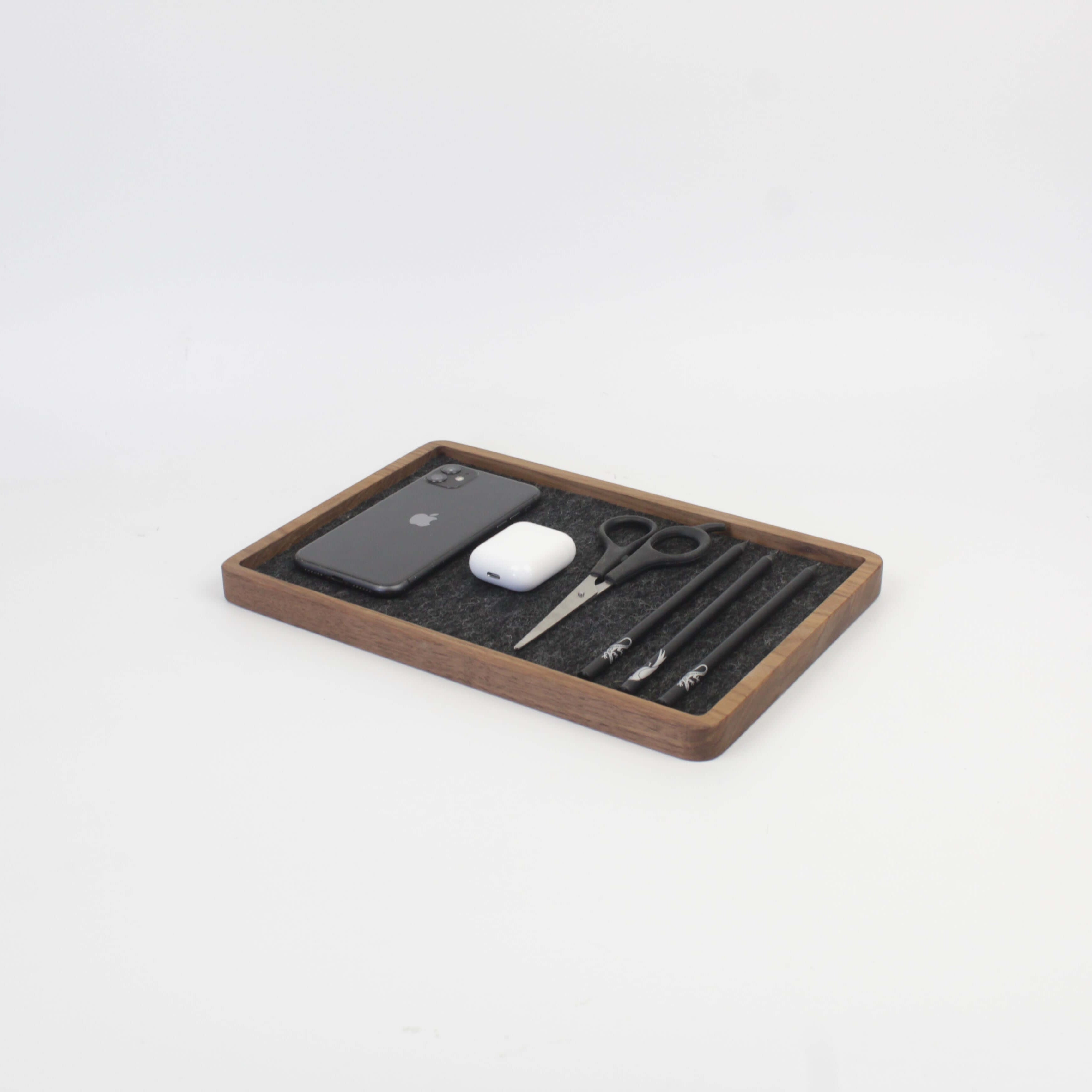 Walnut catch all tray holding a phone, AirPods, scissors, and pens, perfect for desk organization.