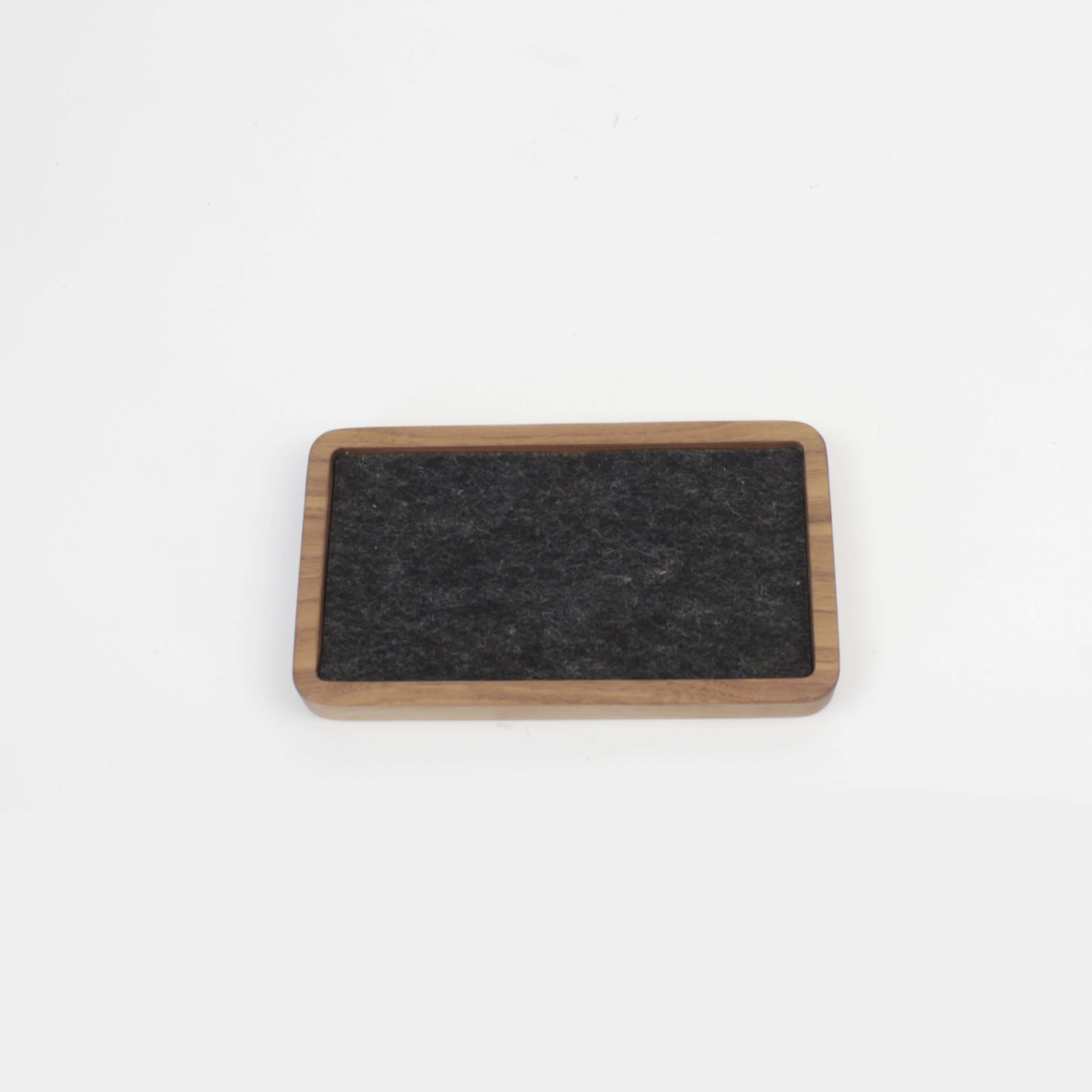 Walnut desk tray with felt surface for organizing small accessories and maintaining a clutter-free space.