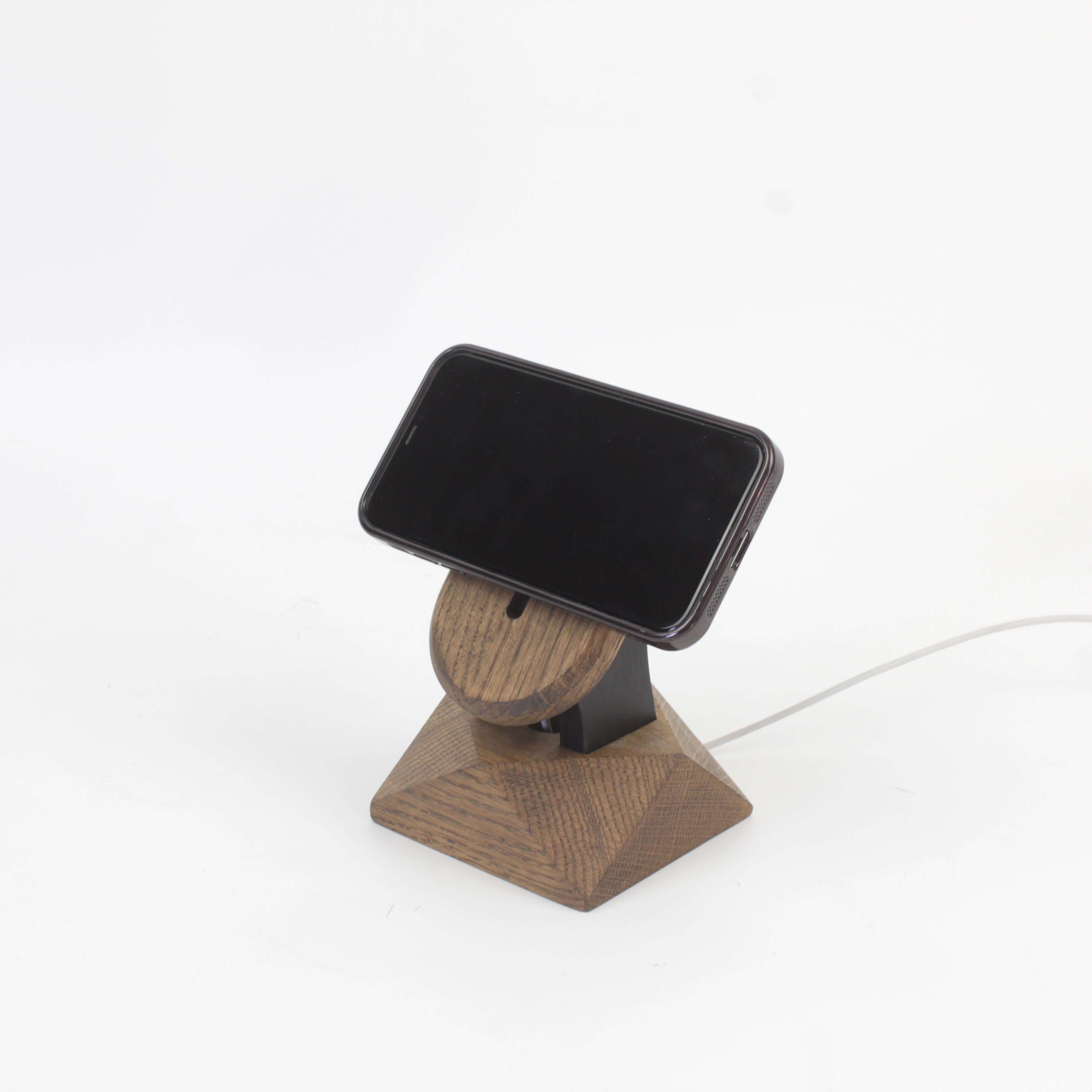MagSafe iPhone stand in brown oak with a phone, showcasing a minimalist design for iPhone wireless charging.