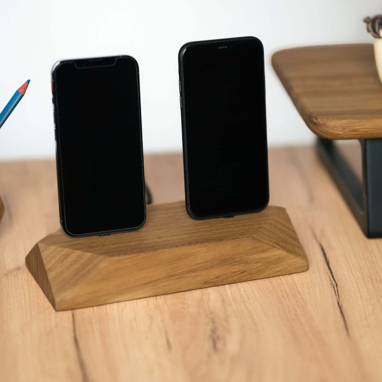Dual phone dock charging station in brown oak, holding two smartphones on a stylish wooden desk.