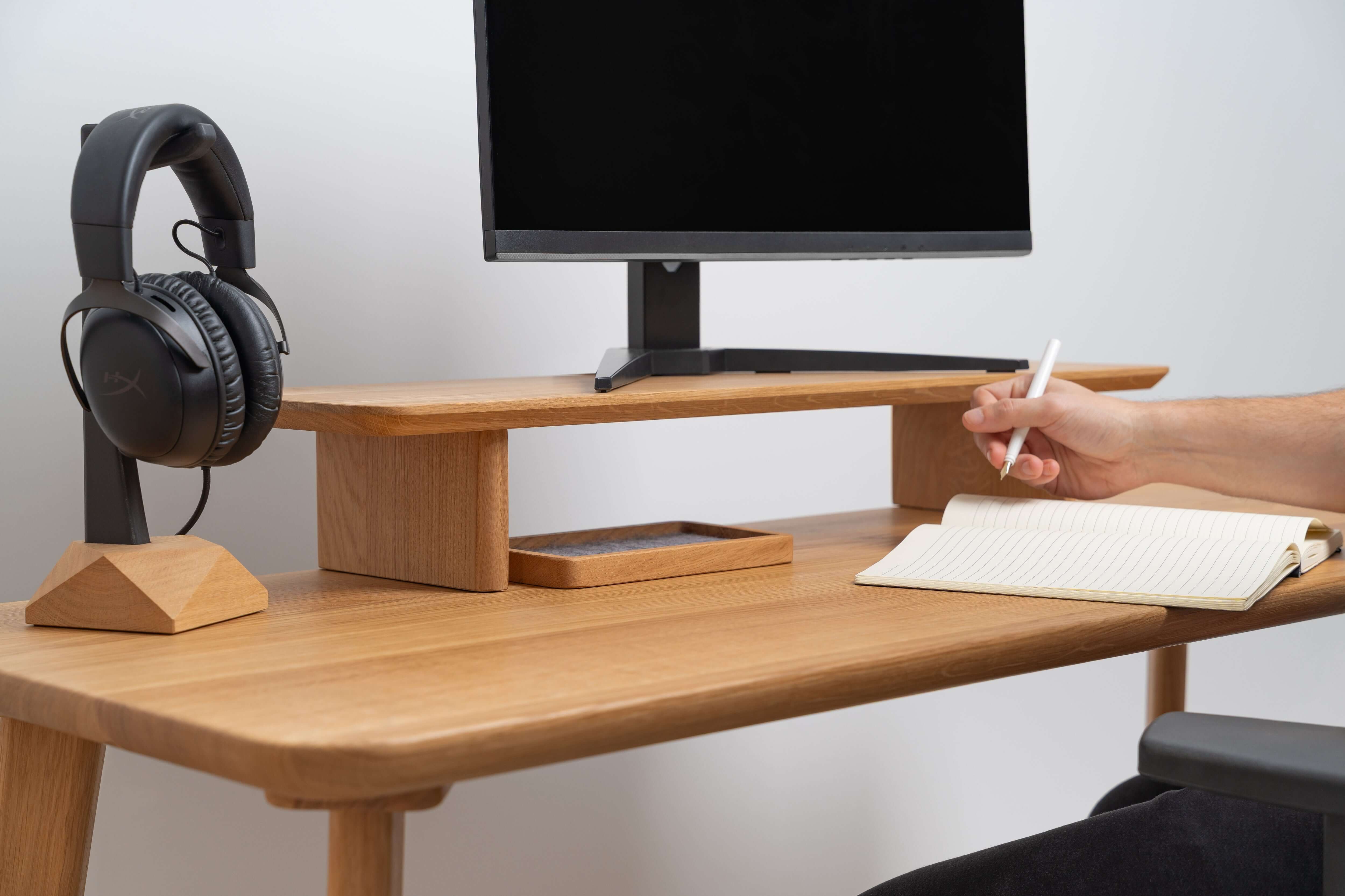 Wooden Table Top used as a workspace with a computer monitor, headphones, and notepad.