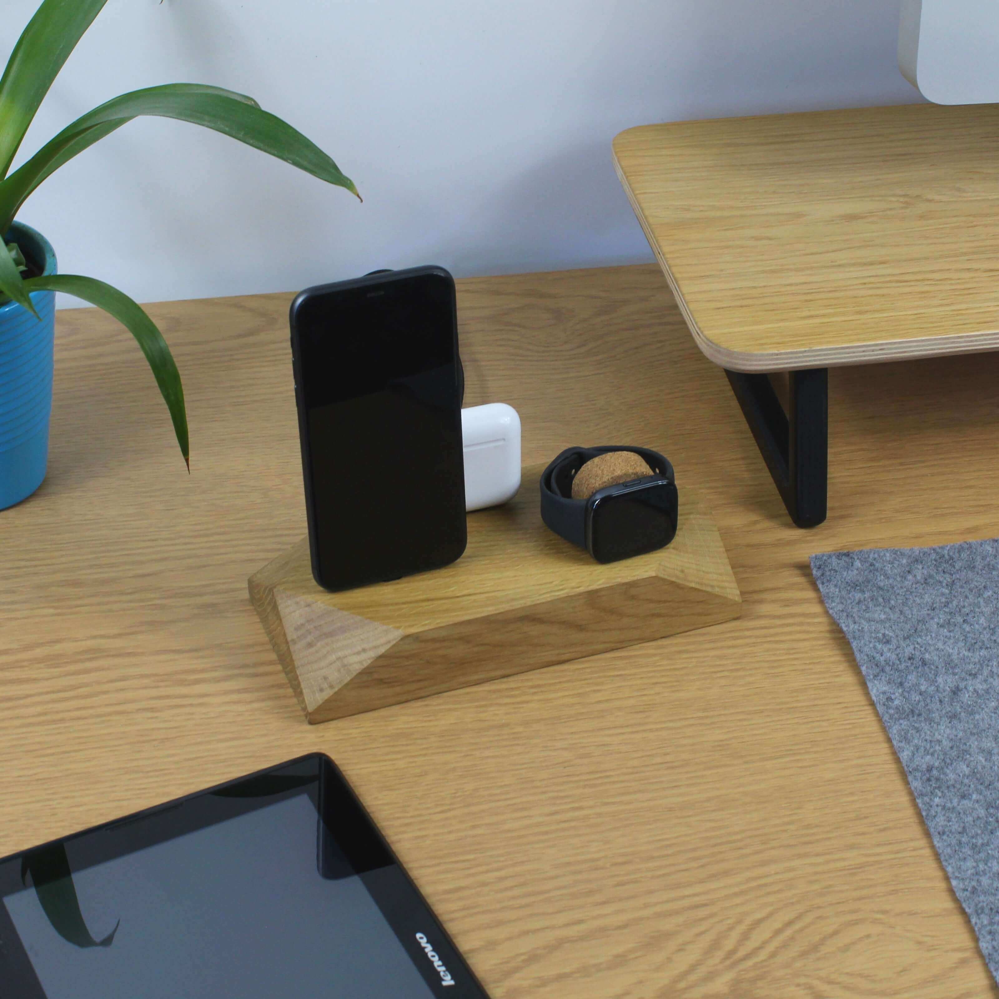 Triple Docking Station in oak, holding two smartphones and an Apple Watch on a stylish desk setup.