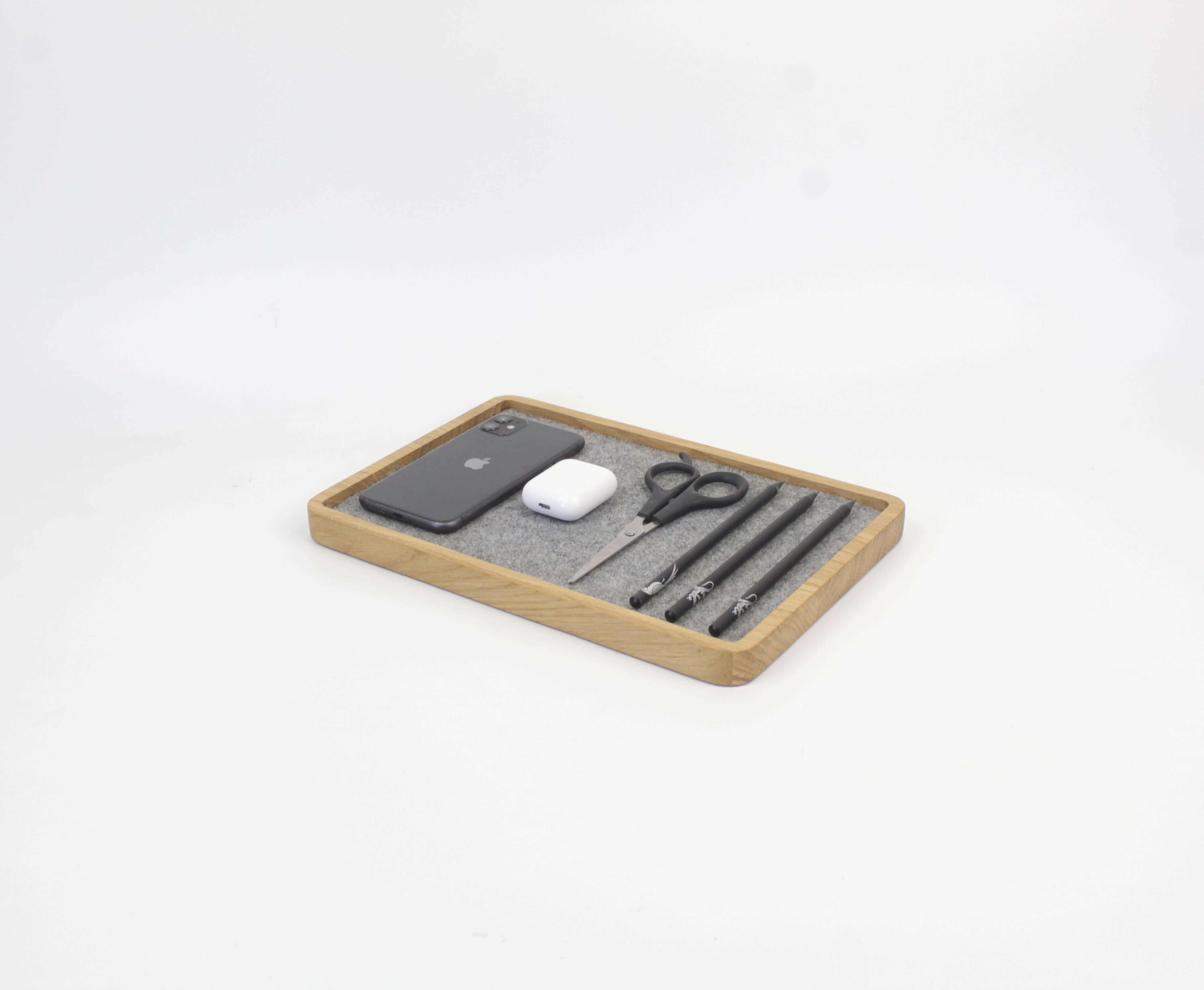 Catch all tray in oak with phone, AirPods, scissors, and pens for desk organization.