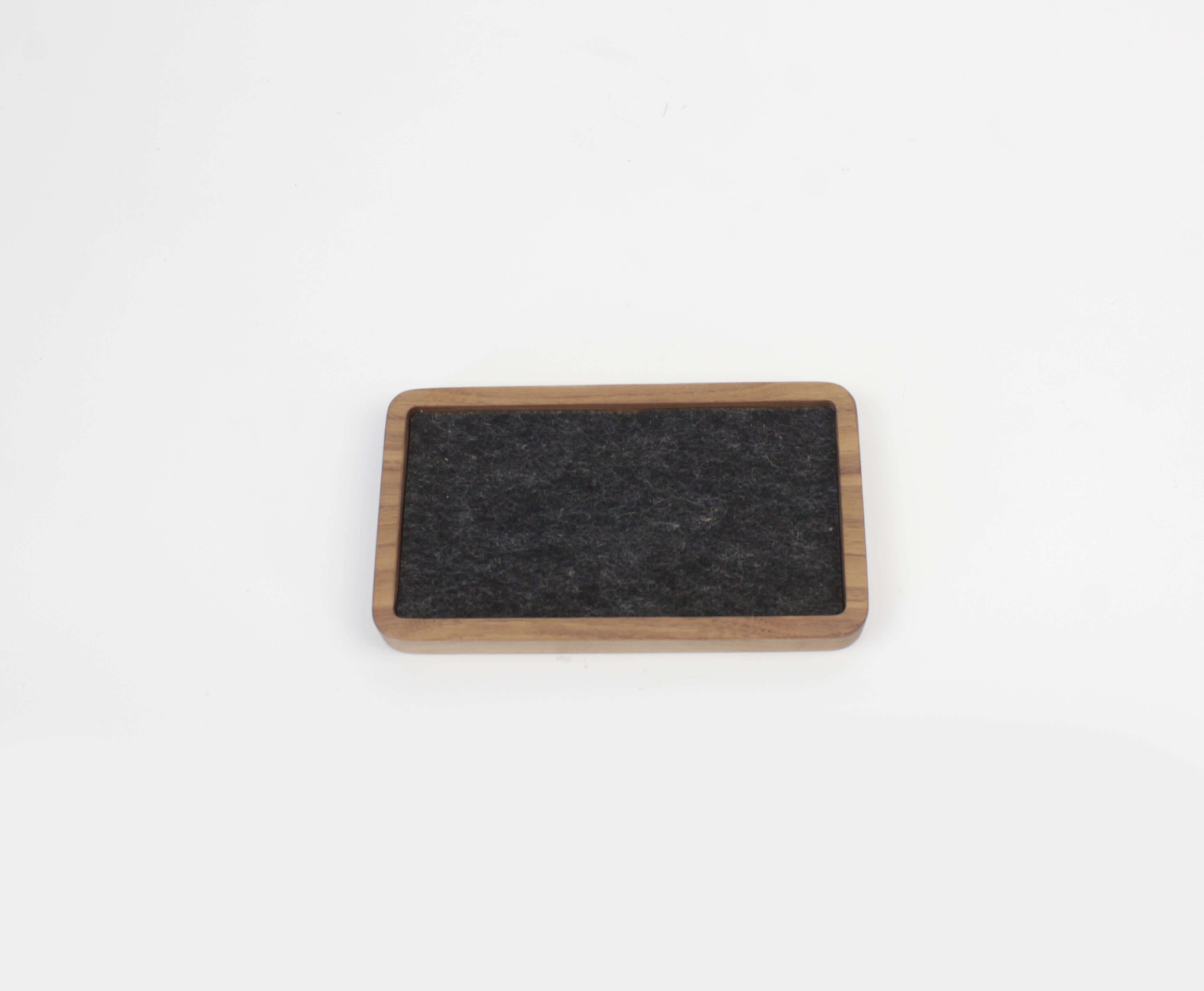 Walnut desk tray with felt surface for organizing small accessories and maintaining a clutter-free space.