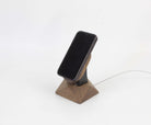 Handcrafted brown oak MagSafe stand holding an iPhone, designed for wireless charging and adding elegance to your space.