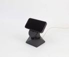 Handcrafted black oak MagSafe iPhone stand with a phone charging, showcasing modern design for iPhone accessories.