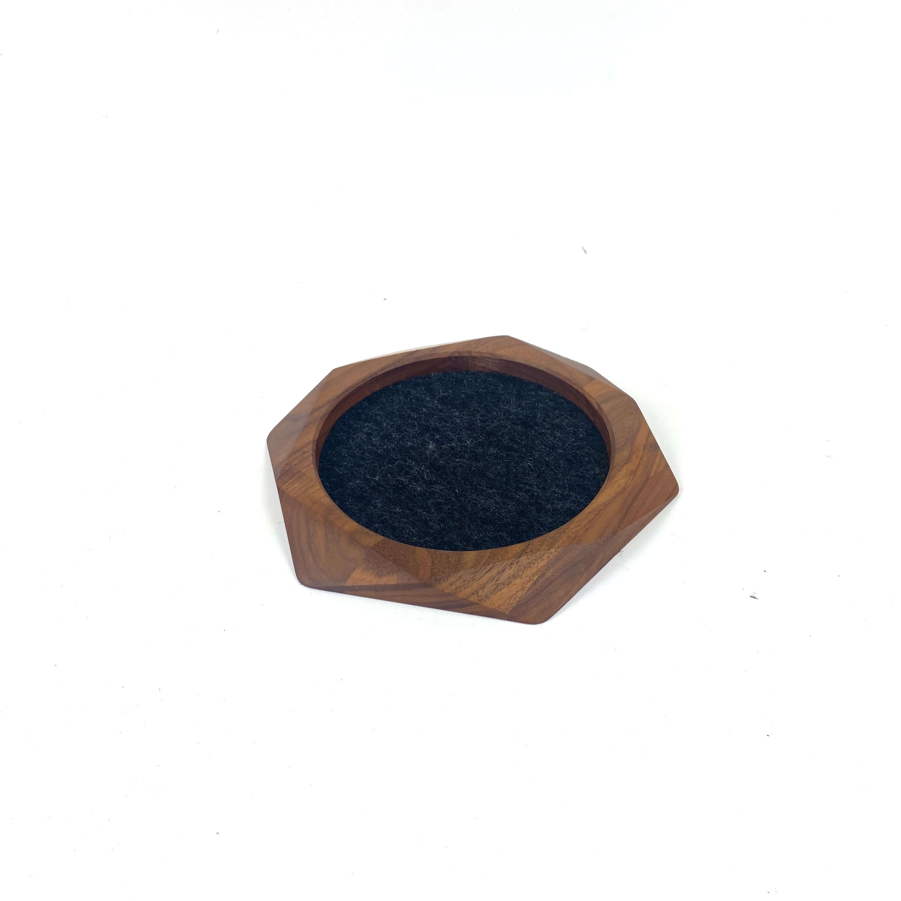 Geometric wooden tray made of walnut with soft black felt lining for organizing small items.