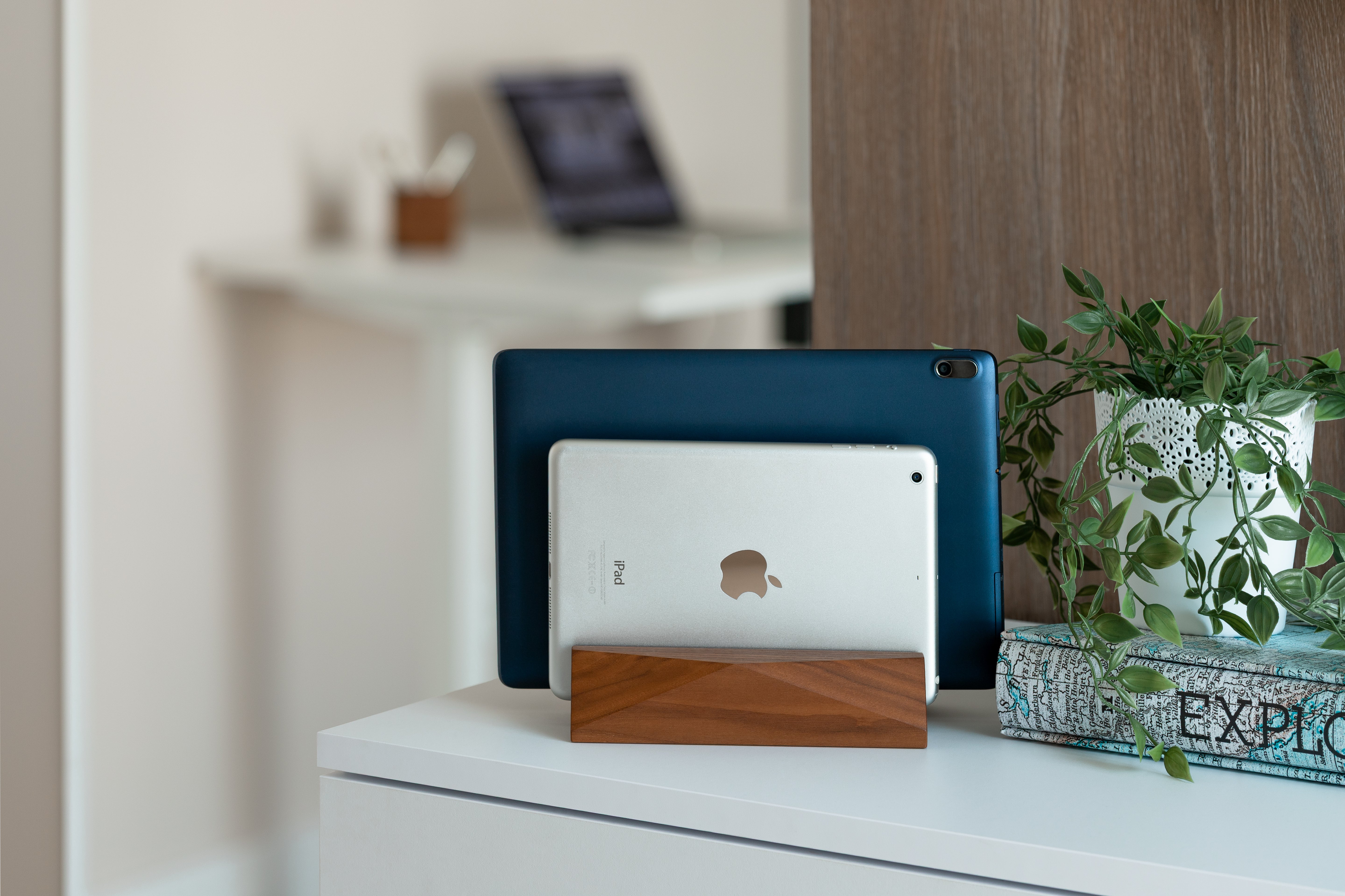Dual Laptop Dock - Walnut holding two tablets on a minimalist desk with greenery in a stylish office setting.